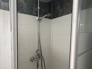 Eine Dusche mit Duschkopf, Wandarmatur und Handbrause.