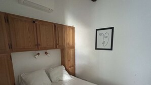 Ein Einzelbett mit Holz Kopfteil, einer weißen Wand und einem gerahmten Bild.
