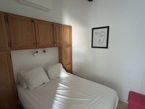 Ein Einzelbett mit Holz Kopfteil, einer weißen Wand und einem gerahmten Bild.