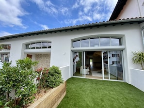 A modern house with a well-maintained lawn, large windows, and a stone wall. - Terraced house in city center - 4 guests (Louhossoa)