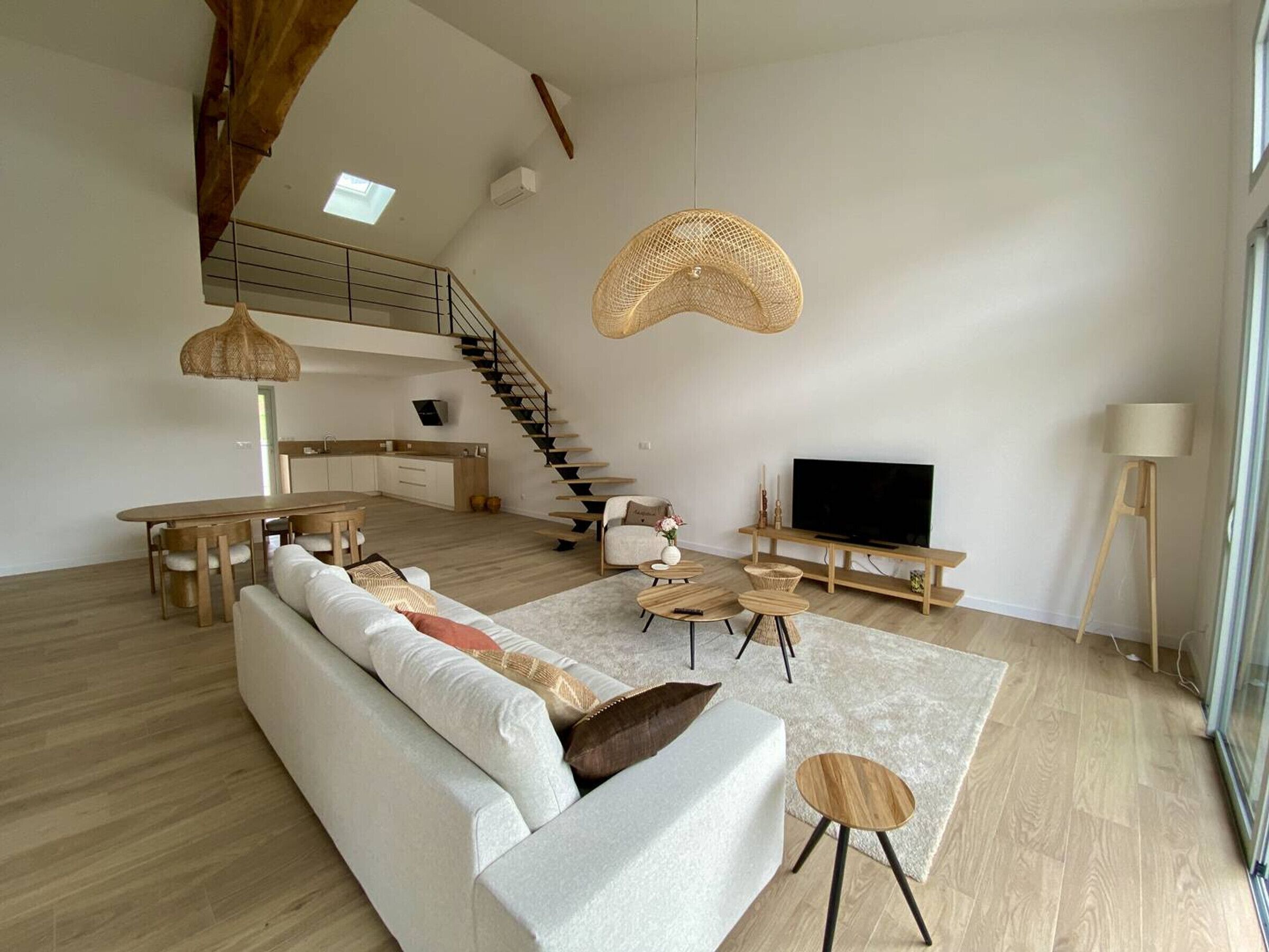 Ein geräumiger Wohnbereich mit Sofa, Couchtisch, TV-Möbel und einer Treppe zu einer oberen Ebene.