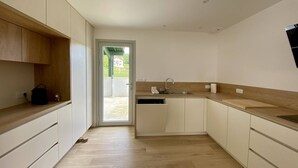 Een moderne keuken met witte kastjes, een houten aanrechtblad en een ingebouwde vaatwasser.