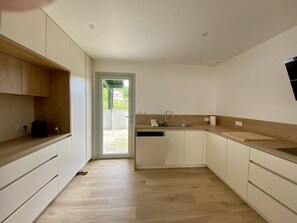 A modern kitchen with white cabinets, a wooden countertop, and a built-in dishwasher. - Terraced house in city center - 4 guests (Louhossoa)