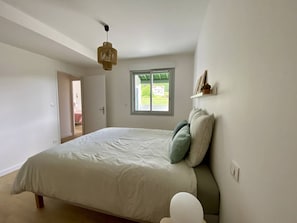 A bedroom with a bed, a window, a hanging light fixture, and a door leading to another room. - Terraced house in city center - 4 guests (Louhossoa)