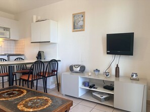 Ein kompakter Wohnbereich mit Essbereich, Küche und einem an der Wand montierten Fernseher.