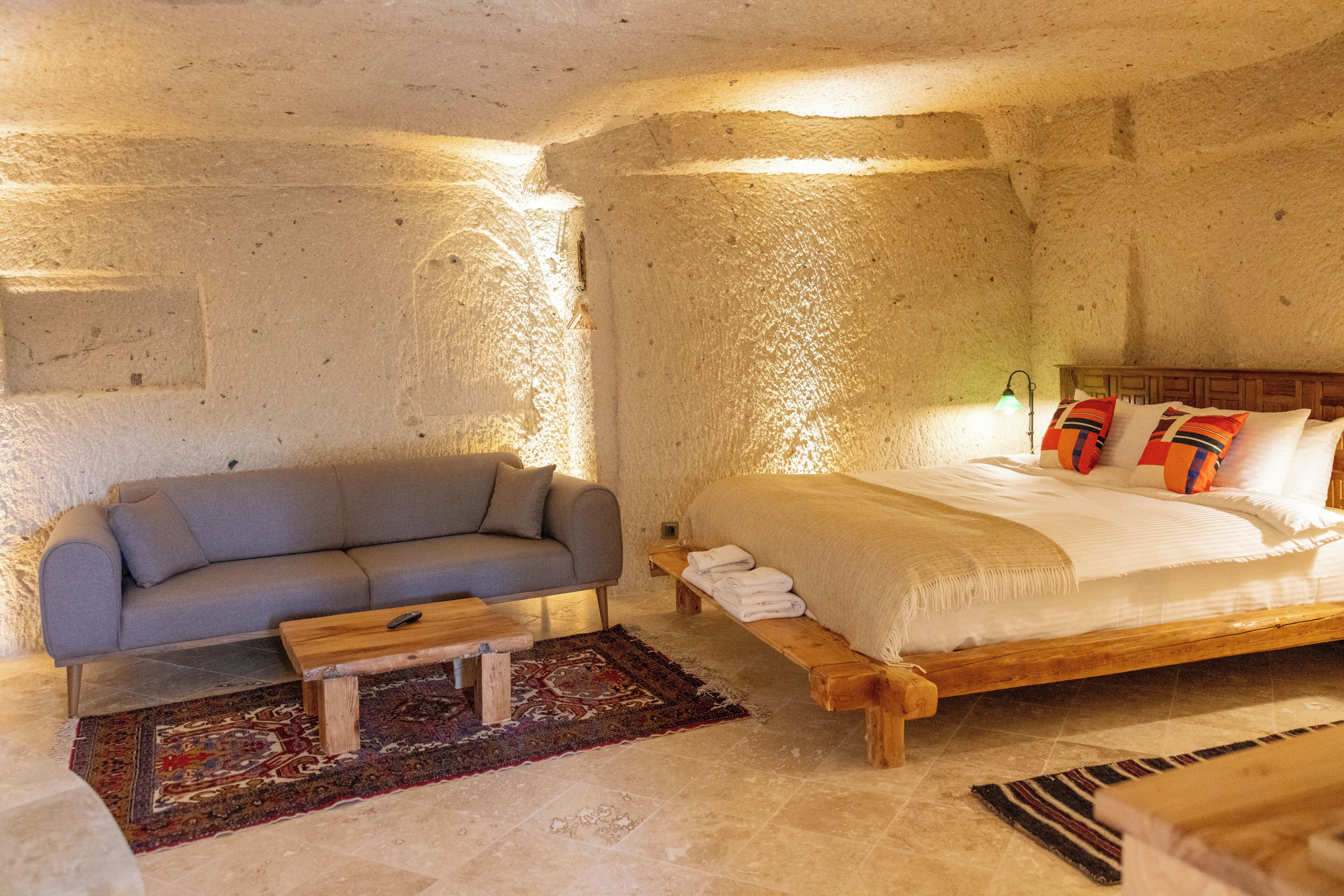 A stone-walled room with a bed, a sofa, and a wooden table.