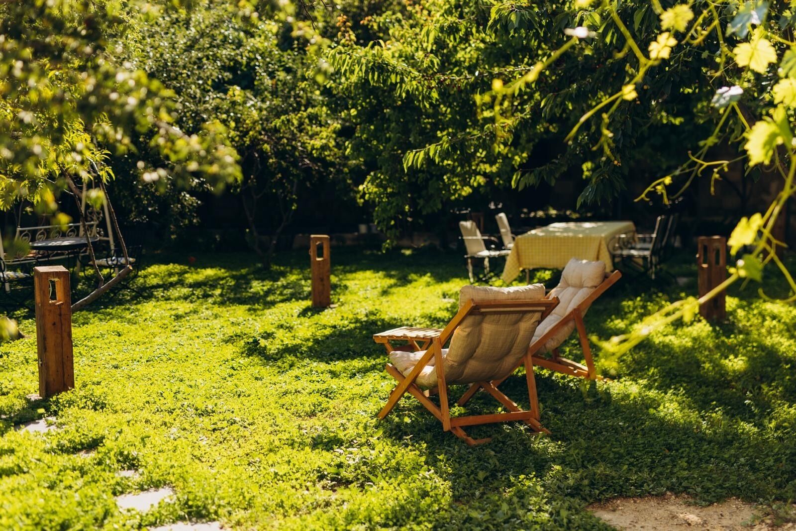 A garden area with a wooden chair and a table, surrounded by lush greenery.