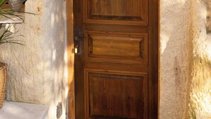A wooden door with a circular emblem, a stone wall, and a potted plant. - Soul of Cappadocia Hotel (Urgup)
