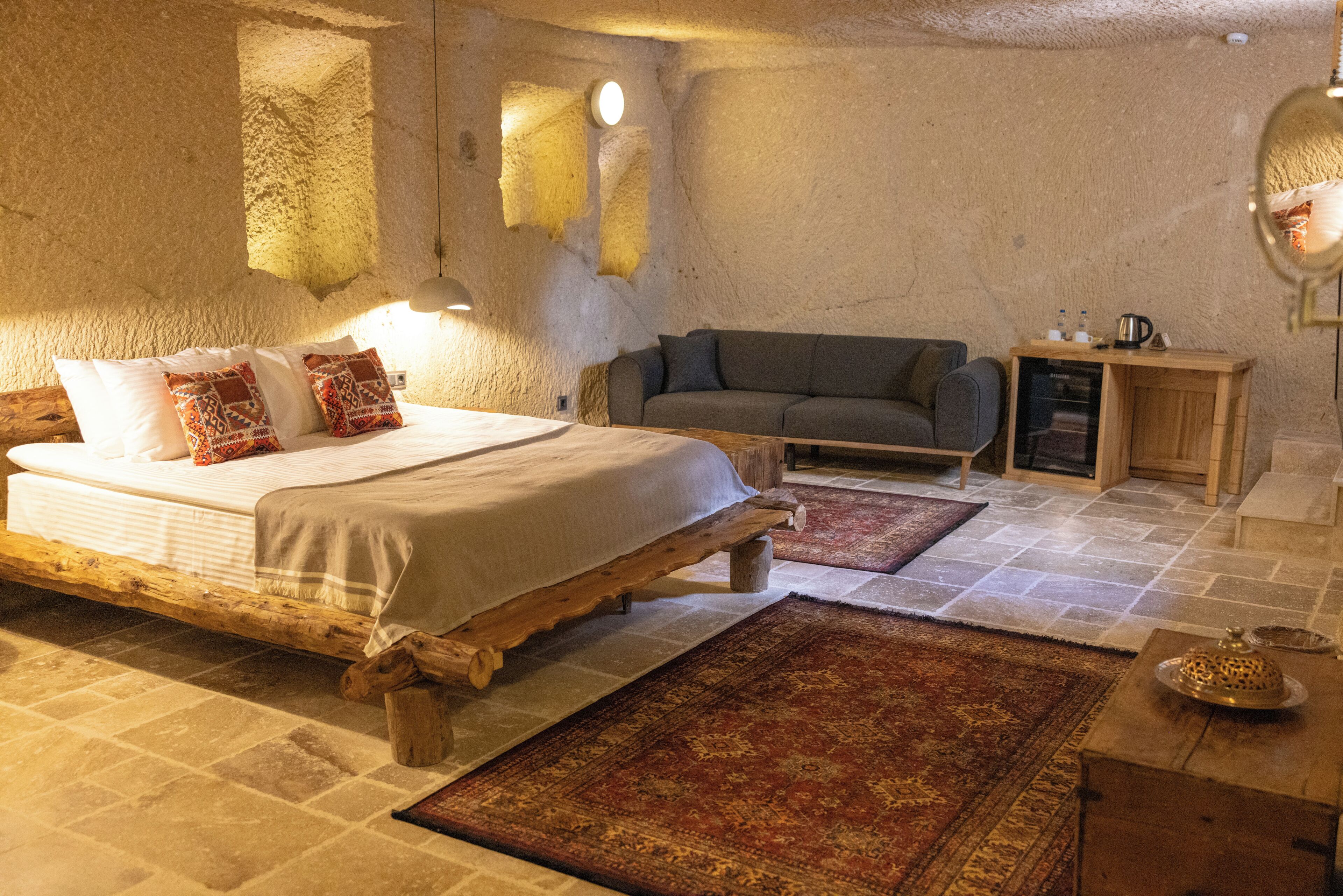 A rustic bedroom with a wooden bed, a sofa, a small cabinet, and a rug.