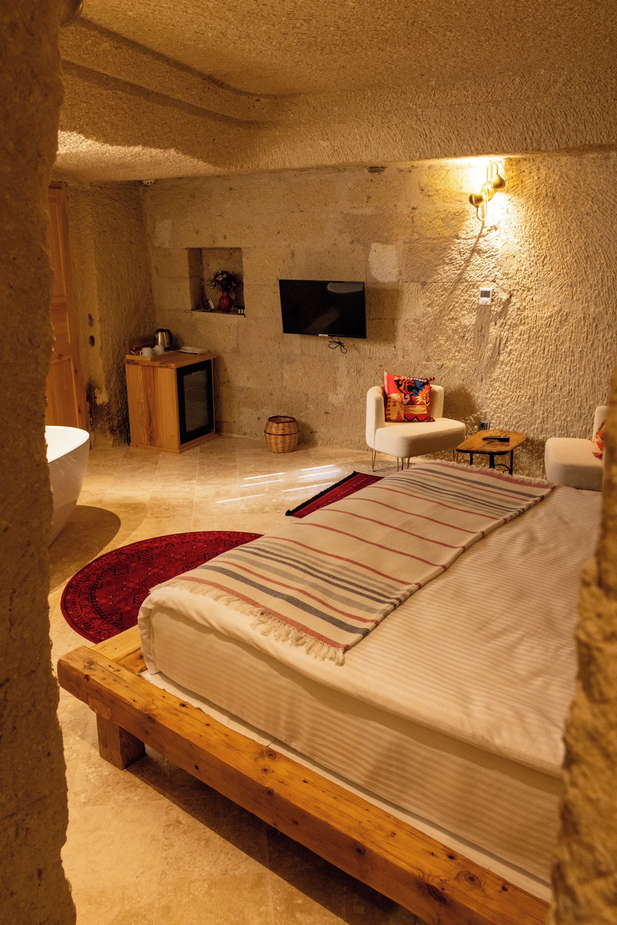 Ein rustikales Schlafzimmer mit einem Holzbett, einem Fernseher, einem kleinen Tisch und einem Stuhl.