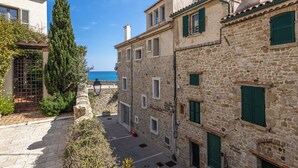 A narrow street with stone buildings, a gate, and a view of the sea. - (018) Le Nid des Remparts (Antibes)