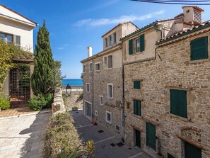 Eine enge Gasse mit Steinhäusern, einem Tor und Blick aufs Meer.