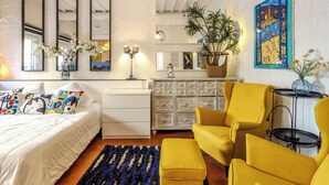 A bedroom with a bed, a dresser, a mirror, a lamp, and a chair. - (018) Le Nid des Remparts (Antibes)