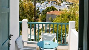 A balcony with a table and chairs, a view of a hillside with white buildings, and a clear sky. - Hotel Elena -sunny Seaside Balcony Suite in Skyros (Skiros)
