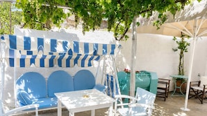 A patio area with a blue sofa, white chairs, a small table, and a green barrel. - Hotel Elena - Cozy Seaside Double Suite in Skyros (Skiros)