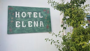 A green sign with 'HOTEL ELENA' written on it, mounted on a white wall. - Hotel Elena - Cozy Seaside Double Suite in Skyros (Skiros)