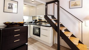 Una cucina moderna con isola centrale, forno integrato e una scala in legno.