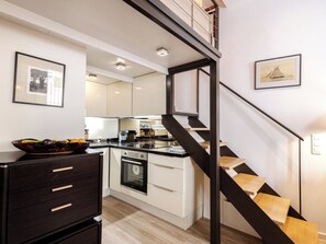 Eine moderne Küche mit einer zentralen Kochinsel, einem eingebauten Backofen und einer Holztreppe.