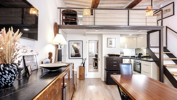 Una cucina moderna con zona pranzo, travi in legno e una scala.
