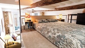 Una camera da letto con un letto grande, travi in legno, una scrivania con una lampada e vista all'aperto.
