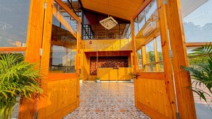 A wooden reception area with a reception desk, a chandelier, and potted plants. - Corbett Hidden Grove (Ramnagar)
