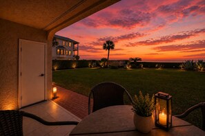 Une terrasse avec une table et des chaises, un pot de fleurs et une bougie allumée.