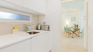 Una cucina moderna con mobili bianchi, un lavello in acciaio inox, un tostapane e un bollitore.