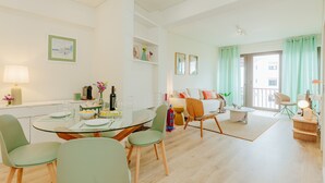Un soggiorno moderno con zona pranzo, divano e balcone con tende.