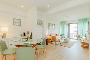 Ein modernes Wohnzimmer mit Essbereich, einer Sofagarnitur und einem Balkon mit Vorhängen.
