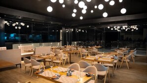 A modern restaurant with round tables, chairs, and pendant lighting. - Royal Avenue Kandy (Kandy)