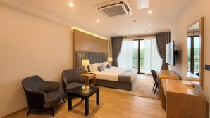 A hotel room with a bed, two armchairs, a desk, a TV, and a balcony with curtains. - Royal Avenue Kandy (Kandy)