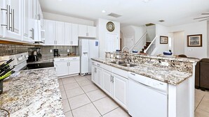 A modern kitchen with white cabinets, granite countertops, and a built-in dishwasher. - Upstay Disney Getaway With Pool Game Room (Davenport)
