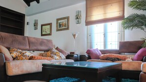 A living room with a brown sofa, a glass coffee table, and a blue rug. - Villa Rural El Mayorazgo en Saleres - Granada (Saleres)
