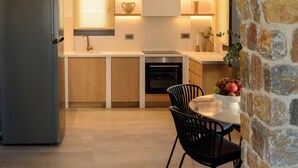 Een moderne keuken met een stenen boog, houten kasten, een ingebouwde oven en een eethoek met tafel en stoelen.