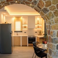 Una cocina moderna con un arco de piedra, armarios de madera, horno empotrado y comedor con mesa y sillas.