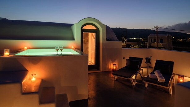 Een terras op het dak met een jacuzzi, lounge stoelen, kaarsen en uitzicht op het landschap.