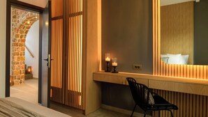 Een moderne hotelkamer met een groot bed, een houten scheidingswand, een bureau met een spiegel en een stoel.