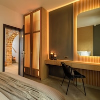 Una habitación de hotel moderna con una cama grande, un separador de madera, un escritorio con espejo y una silla.