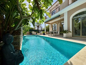 A swimming pool with a Buddha statue, outdoor furniture, and a building with balconies. - ALGARVE STUNNING VILLA WITH POOL by HOMING (Santa Bárbara de Nexe)