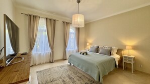 Een slaapkamer met een bed, nachtkastjes, een bureau en een televisie.