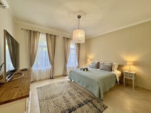 A bedroom with a bed, bedside tables, a desk, and a television. - ALGARVE STUNNING VILLA WITH POOL by HOMING (Santa Bárbara de Nexe)