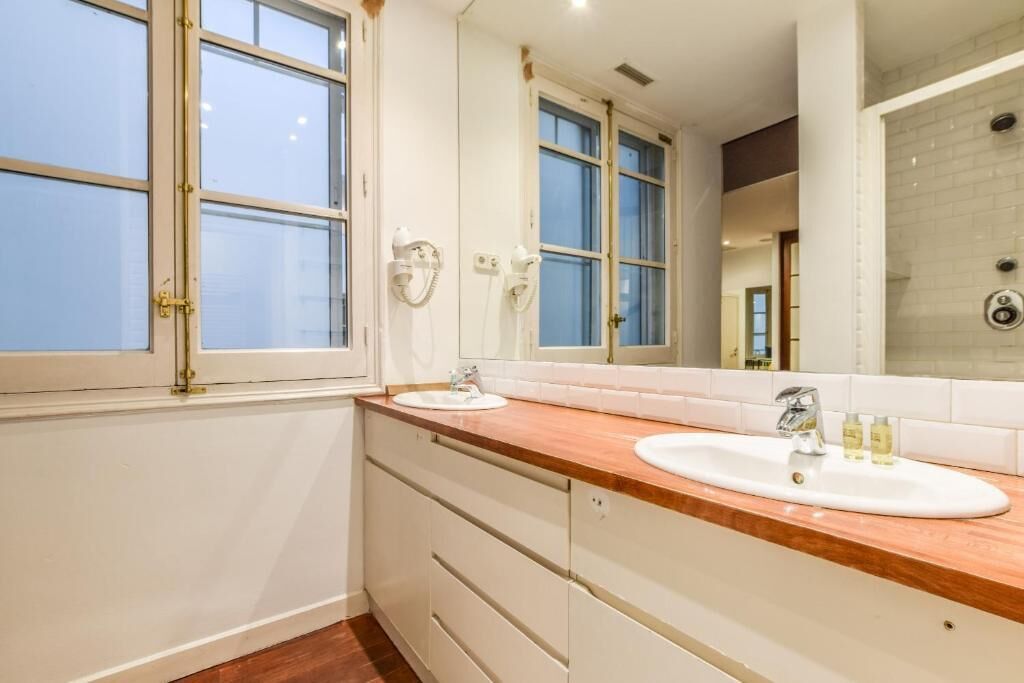A bathroom with two sinks, a large mirror, and a shower area.