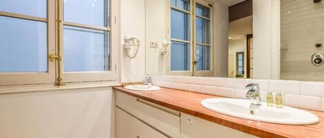 A bathroom with two sinks, a large mirror, and a shower area.
