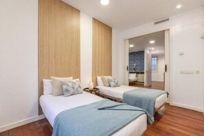 Ein Hotelzimmer mit zwei Betten, Holzvertäfelung, einer Wand aus Stein und Blick ins Badezimmer.