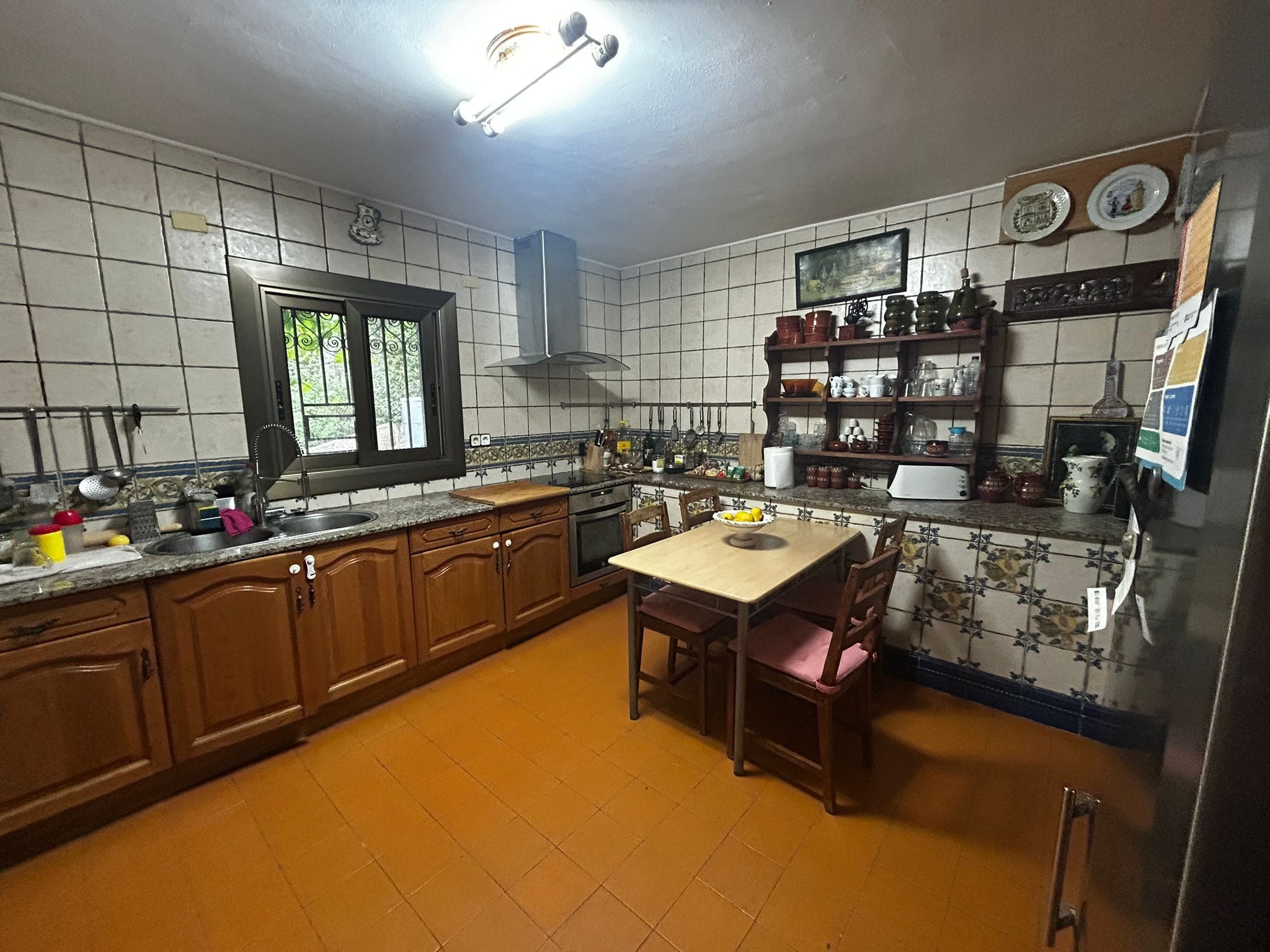 A kitchen with wooden cabinets, a window, a stove, and a dining table with chairs.