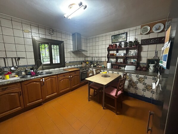 A kitchen with wooden cabinets, a window, a stove, and a dining table with chairs.
