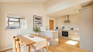 Una cocina moderna con una isla de madera, un comedor con mesa y sillas, y vistas al exterior a través de una ventana.