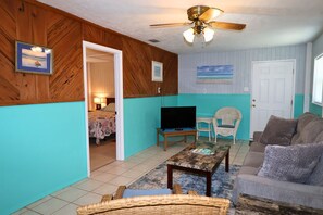 A living room with a television, a sofa, a coffee table, and a ceiling fan. - Budget Friendly Apartment with Ample Boat Parking! (Cedar Key)