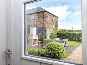 A stone building with a chimney, outdoor seating, and a well-maintained garden. - Duke's Barn (Totnes)