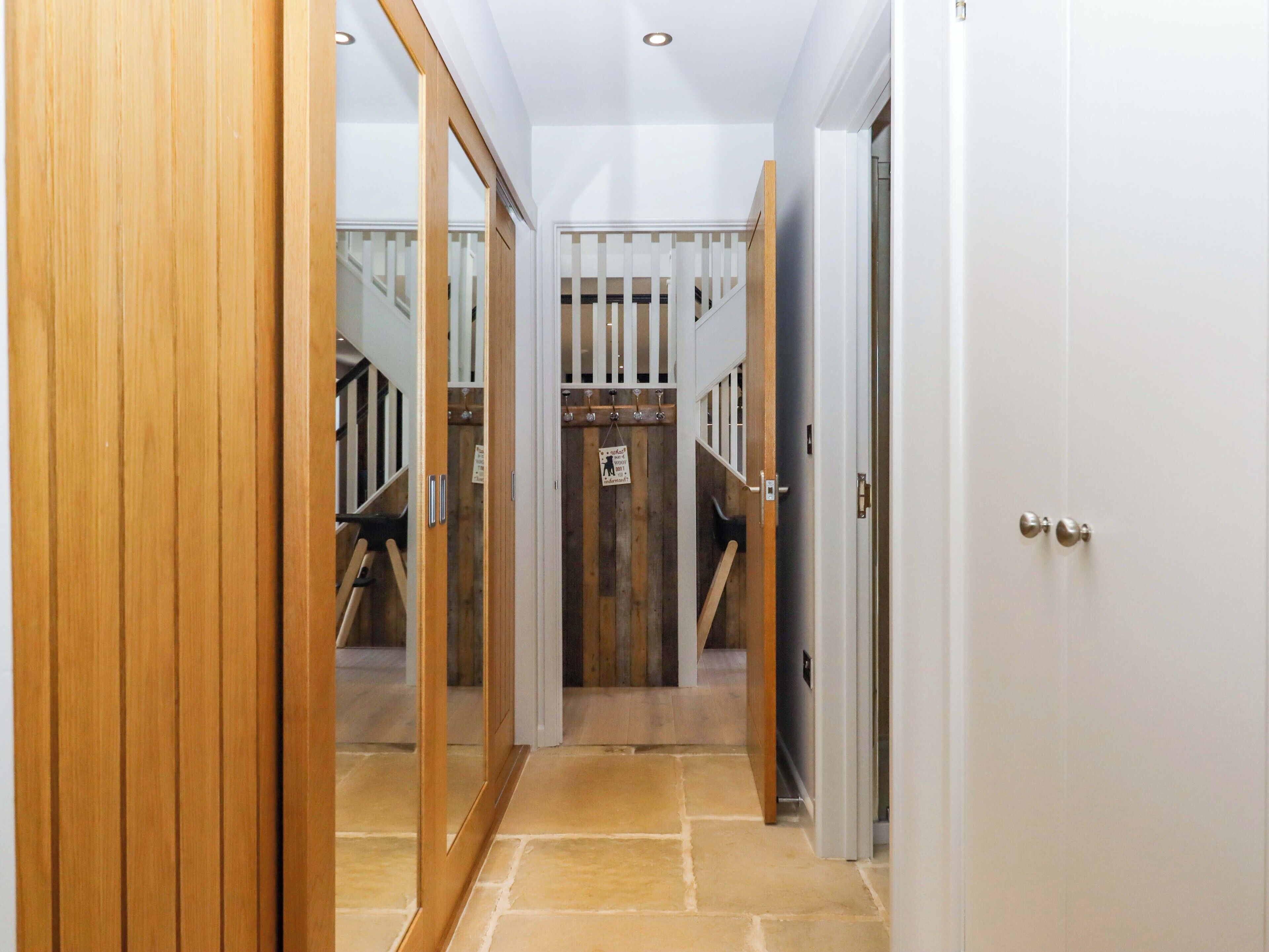 A hallway with wooden doors, a staircase, and a sign indicating a pet-friendly area.